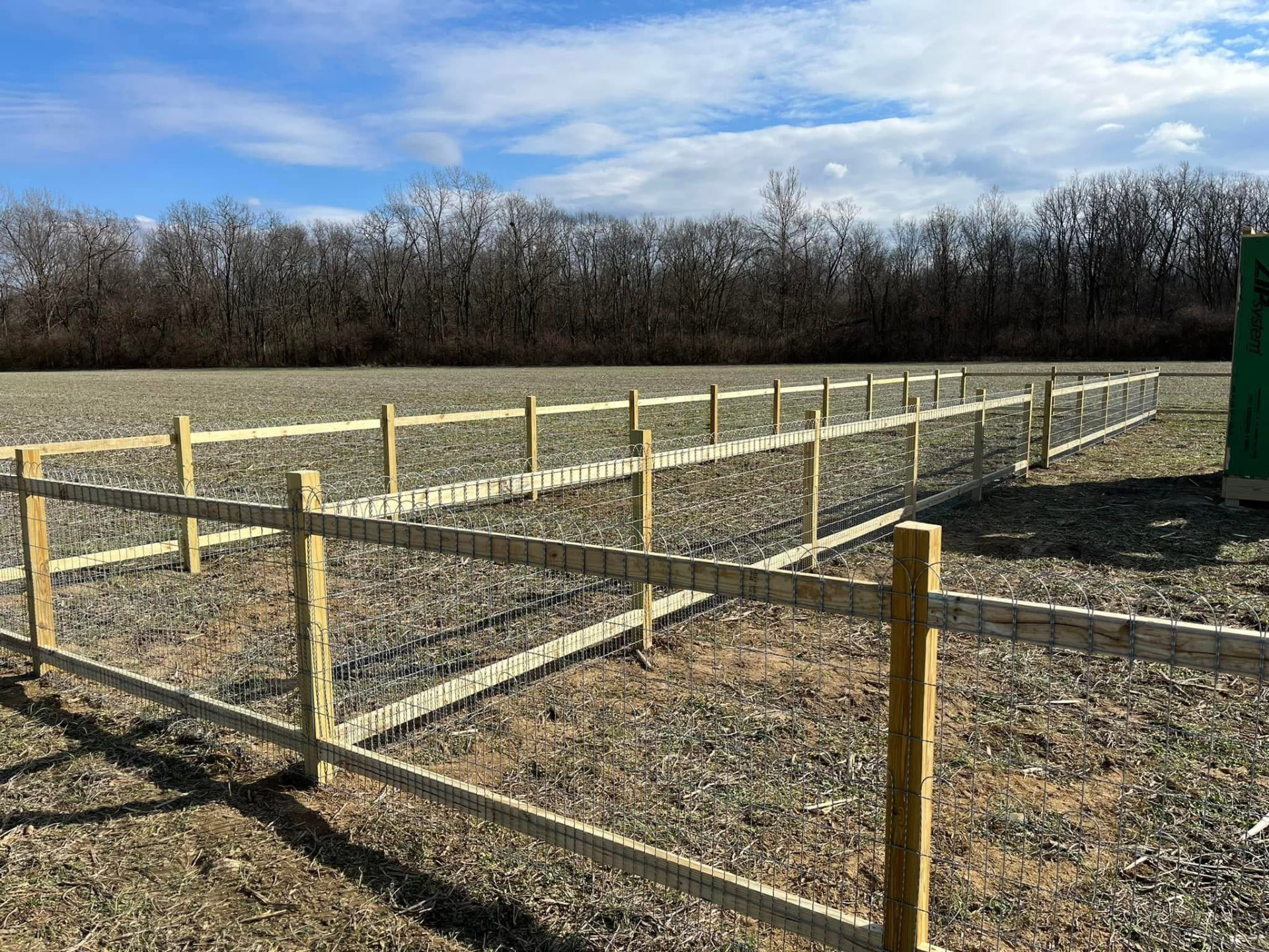 Wood post and woven wire field fence around a build site