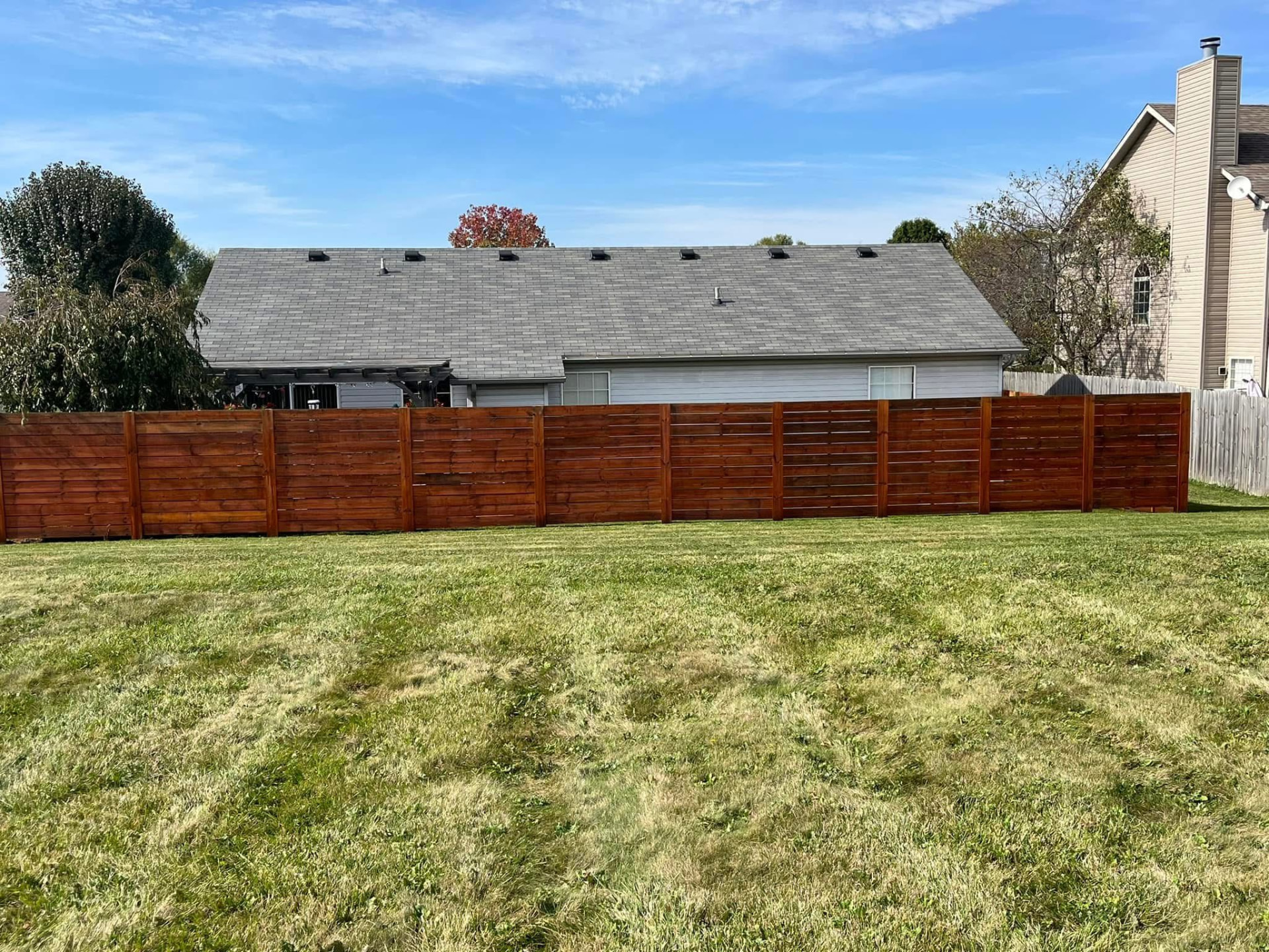 Stained horizontal cedar privacy fence in a backyard
