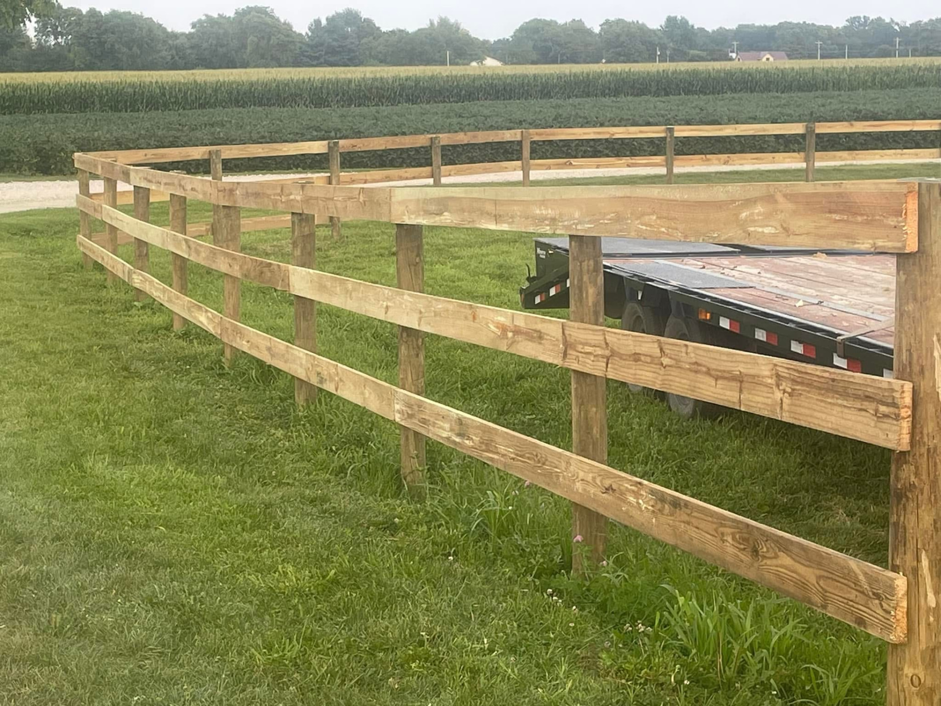 Three-rail wood board fence along a crop field