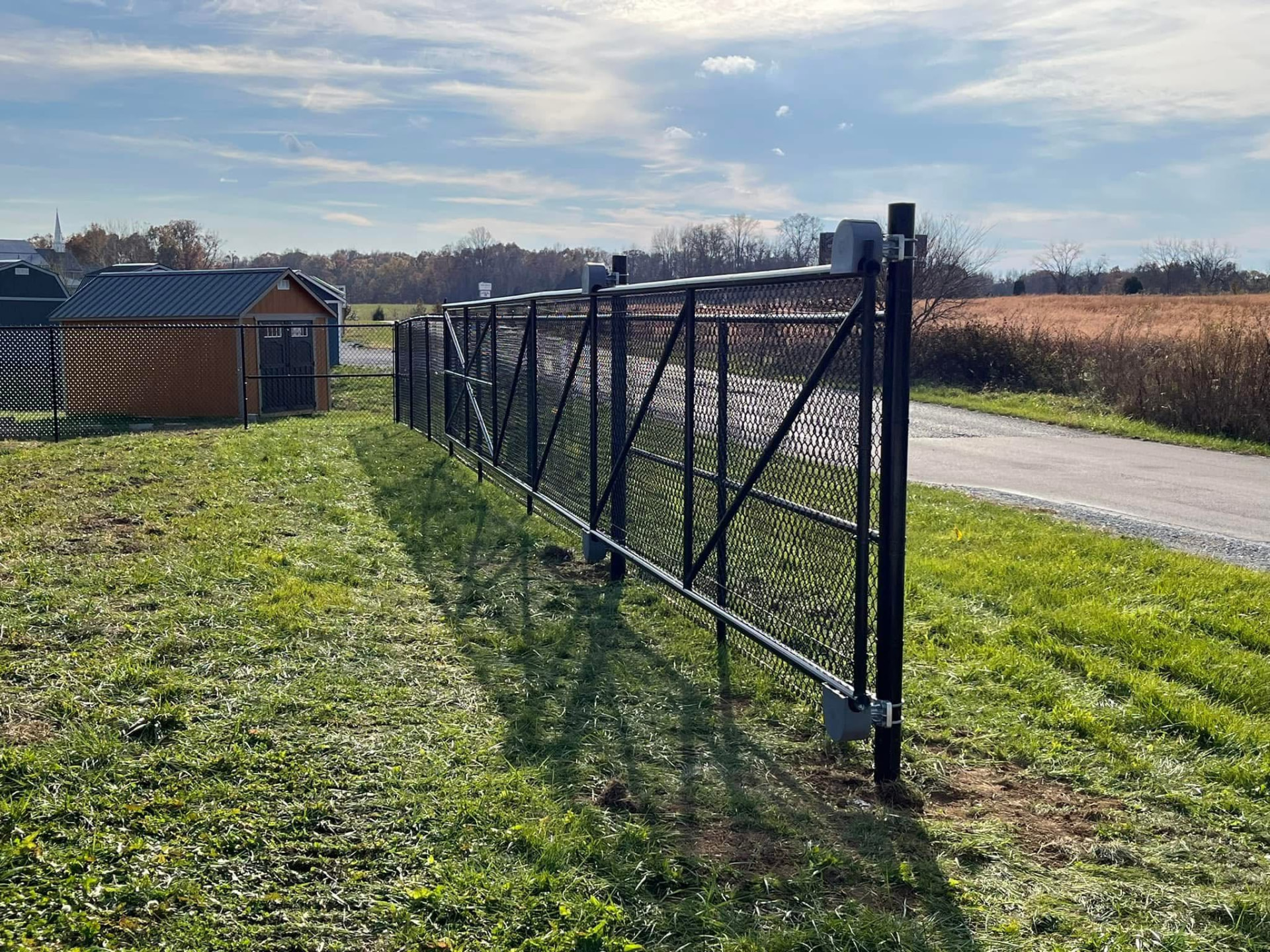 Black chain link cantilever slide gate at a driveway entrance