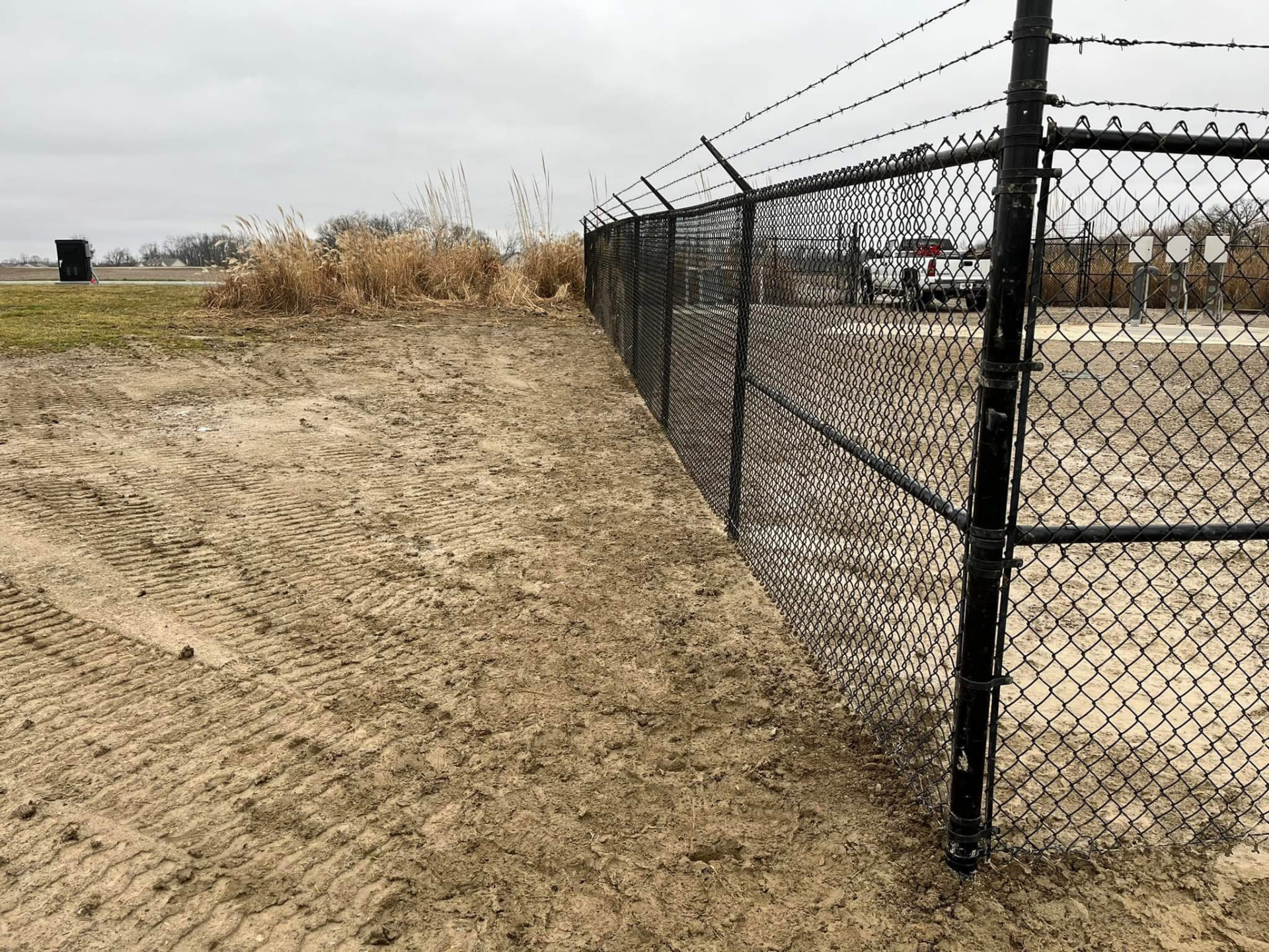 Black chain link security fence with barbed wire
